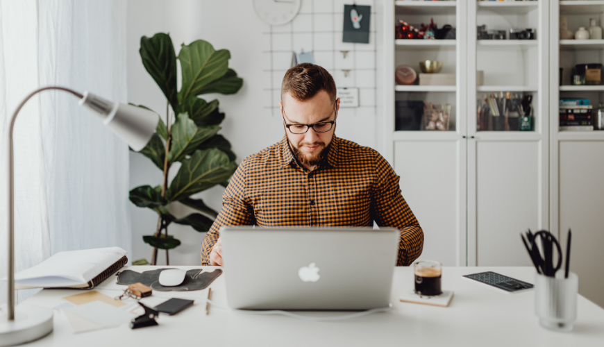 White man working on laptop at desk at home